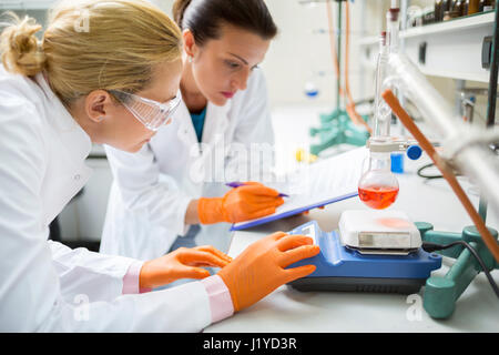 Young female chemical technicians working on experiment in laboratory Stock Photo