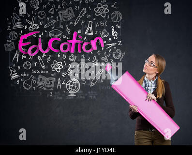 Schoolgirl with big marker writing on the wall word education Stock Photo
