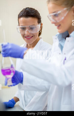 Young female chemical workers analyzing liquid in glassware in laboratory Stock Photo