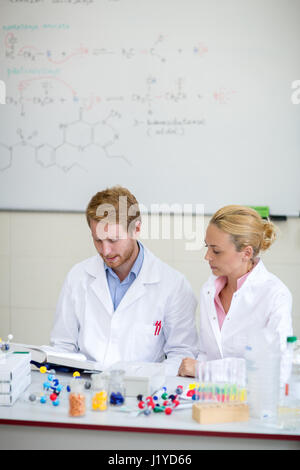 Couple of young chemists prepare lecture in chemical cabinet Stock Photo