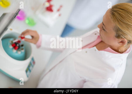 Close up of female chemist putting sample in test tube in device Stock Photo