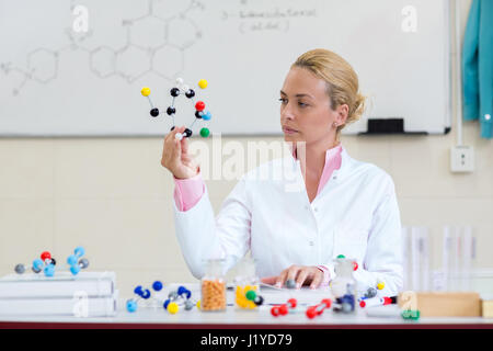 Young chemistry scientist show molecular model and look it in chemical cabinet Stock Photo