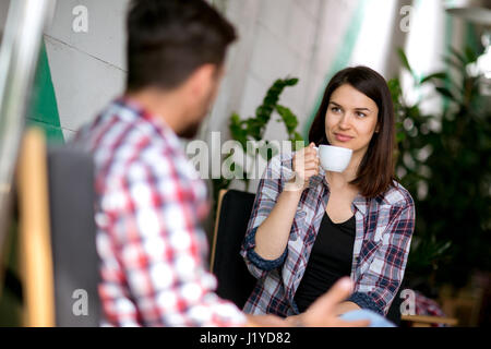 Cute young woman drinking coffee on a first date Stock Photo
