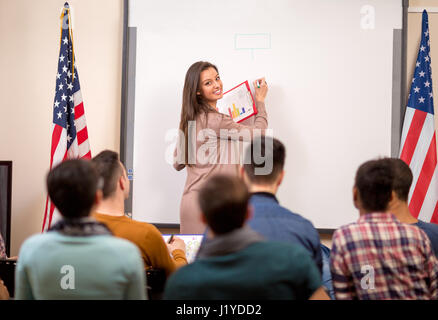 Young lecturer demonstrate diagram on blackboard for her students Stock Photo