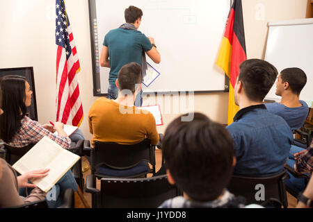 Handsome male lecturer doing task in front of his students  on the blackboard Stock Photo