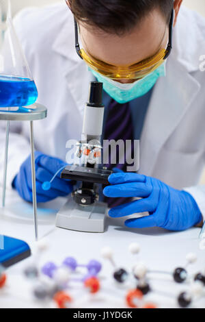 man scientist studying microbiological substance in microscope Stock Photo