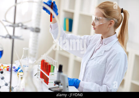 scientist analyzing reaction of some chemicals in test tubes with red liquid Stock Photo