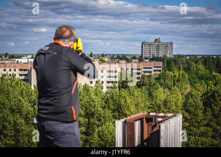 Tourist on a building roof in Pripyat ghost town in Chernobyl Nuclear Power Plant Zone of Alienation around the nuclear reactor disaster in Ukraine Stock Photo