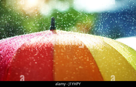 Rain drops falling onto umbella with rainbow colour Stock Photo