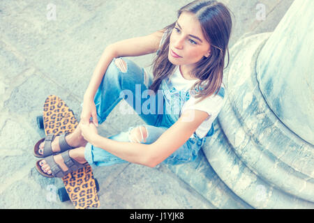beautiful young woman sitting over a spotted skateboard Stock Photo