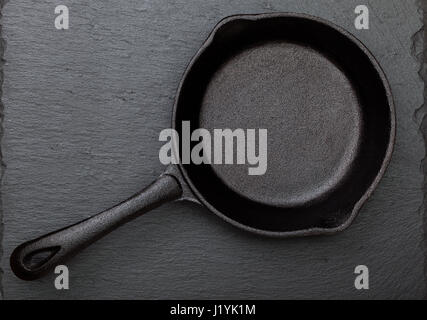 Empty cast-iron frying pan on a black slate background (top view) Stock Photo