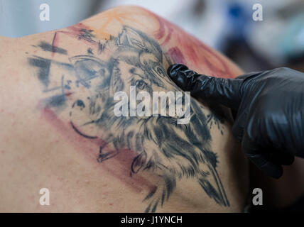 Frankfurt, Germany. 22nd Apr, 2017. A participants of the Internationalen Tattoo Convention shows their body tattooed with a wolf in Frankfurt am Main, Germany, 22 April 2017. Photo: Boris Roessler/dpa Credit: dpa picture alliance/Alamy Live News Stock Photo