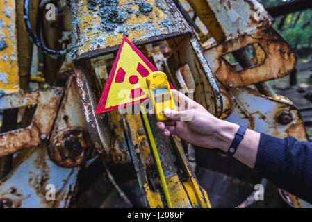 Tourist examine irradiated scrap bucket in Pripyat city of Chernobyl Nuclear Power Plant Zone of Alienation around nuclear reactor disaster, Ukraine Stock Photo