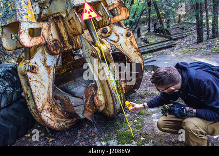 Tourist examine irradiated scrap bucket in Pripyat city of Chernobyl Nuclear Power Plant Zone of Alienation around nuclear reactor disaster, Ukraine Stock Photo