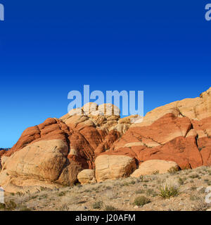 A desr landscape of a Red Rock formation with clear blue sky. Image is set in a sqaure format. Stock Photo