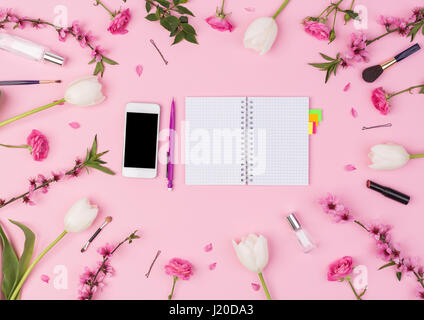 Girly, beauty blog, spring, concept. Feminine bloggerworkspace with notebook, phone, perfume, sakura, rose, tulips flowers and women's accessories on pink background. flat lay, top view Stock Photo