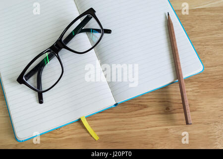 Notebook, pencil and glasses on the wooden table. Stock Photo