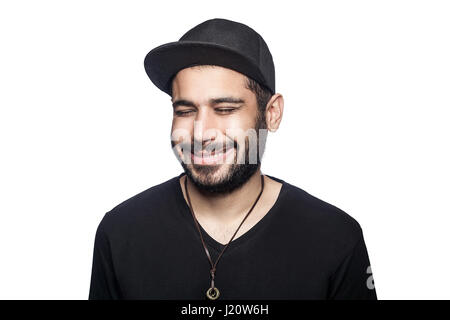 Portrait of young happy smilely man with black t-shirt and cap with closed eyes and toothy smile. studio shot, isolated on white background. Stock Photo