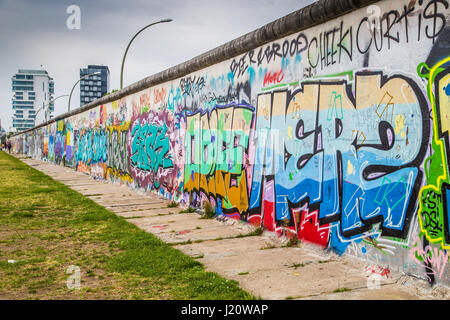 Panoramic view of famous Berlin Wall decorated with colorful graffiti street art at historic East Side Gallery on a moody cloudy day in summer, Berlin Stock Photo