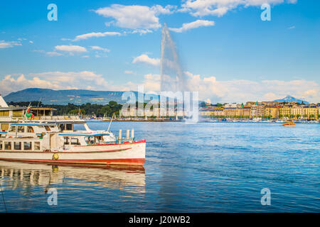 Panorama view of historic Geneva skyline with famous Jet d'Eau fountain and ships at harbor district in beautiful evening light at sunset, Switzerland Stock Photo
