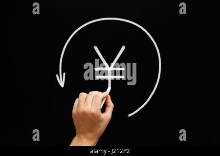 Hand sketching Japanese Yen or Chinese Yuan sign in arrow circle with white chalk on blackboard. Stock Photo