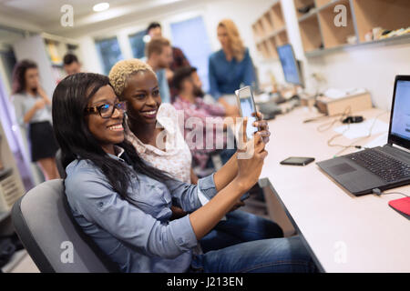 Beautiful female coworkers working at company taking selfie Stock Photo