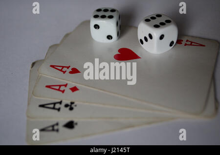 Two white dices on four playing card aces close up Stock Photo