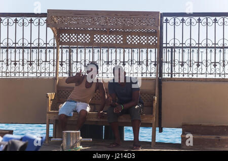 Egypt.Hurgada-October, 6,2016. Two Arab young adult male sitting on a bench showing a thumbs up sign. Stock Photo