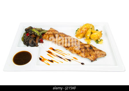 Fish fillet with roasted potatoes, onions and steamed vegetables - zucchini, carrots, peppers and eggplant. Stock Photo