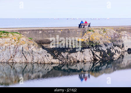 People sit and watch yachts racing in the distance Stock Photo