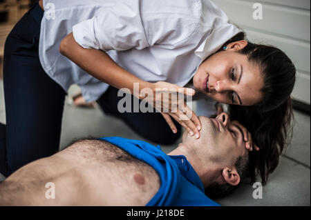 a girl helping a guy after heart attack with cardiopulmonary resuscitation Stock Photo