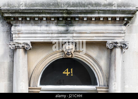 Door captial with face, Doric columns and pediment in London England, UK Stock Photo