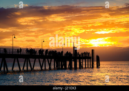 People walking along Glenelg Beach jetty at sunset, Adelaide, South Australia Stock Photo