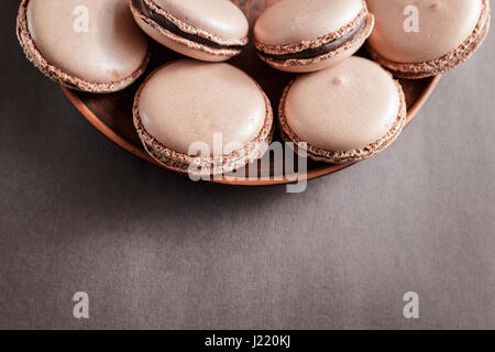Chocolate pastel brown Macarons or Macaroons on a plate over dark background Stock Photo