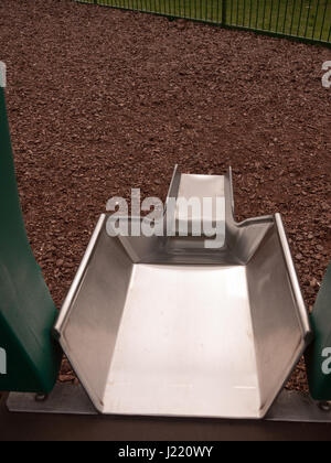 a close up shot of a metal slide in a child's playground with bark wooden chips for safety, accident, no people shining metal, dangerous and fun for c Stock Photo