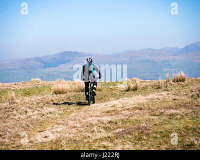 A mountain biker rides along top of Dent fell in the Lake district, Cumbria, England Stock Photo