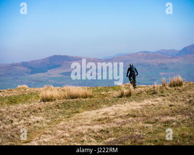A mountain biker rides along top of Dent fell in the Lake district, Cumbria, England Stock Photo