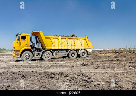 Big hydraulic dump truck is moving into reverse, prepare to unload cargo. Stock Photo