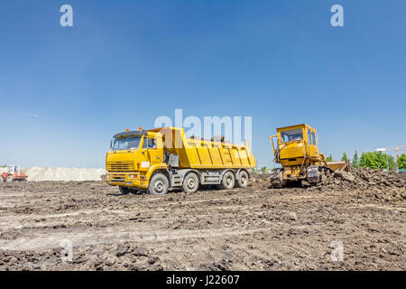 View on heavy bulldozer while he moving, leveling ground at construction site.  Heavy wheels are working at construction site. Stock Photo