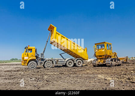 View on heavy bulldozer while he moving, leveling ground at construction site.  Heavy wheels are working at construction site. Stock Photo