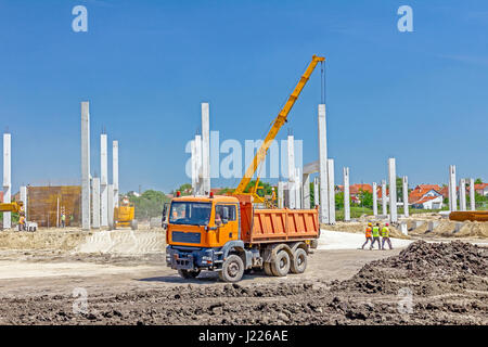 Big hydraulic dump truck is in transport on building site, passing over. Stock Photo