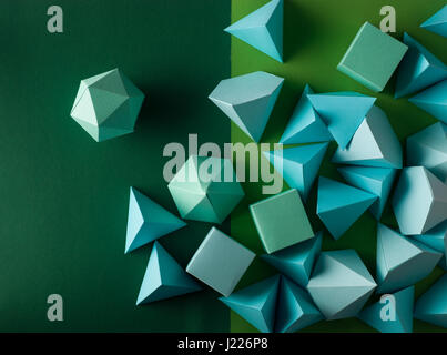 Colorful abstract geometric background with three-dimensional solid figures. Pyramid Dodecahedron prism rectangular cube arranged on green paper. Stock Photo