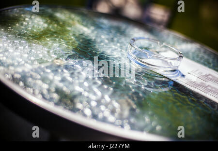 One ashtray on glass table, abstract composition with lot of blur. Stock Photo