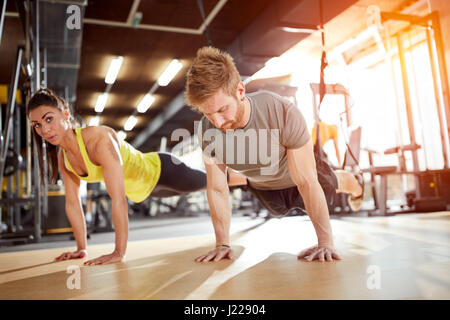 Woman with coach doing hard exercise in gym Stock Photo