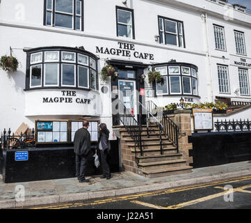 A man and woman look at the menu boards at the famous Magpie Cafe in Whitby, North Yorkshire,England,Uk Stock Photo