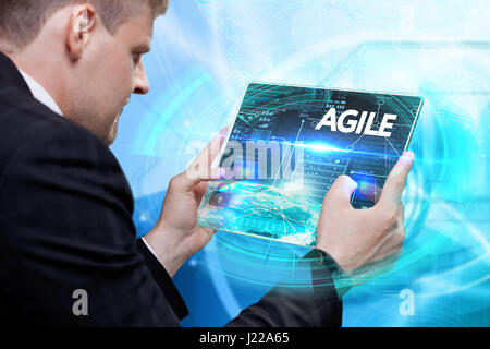 Business, technology, internet and networking concept. Young businessman working on his laptop in the office, select the icon agile on the virtual dis Stock Photo