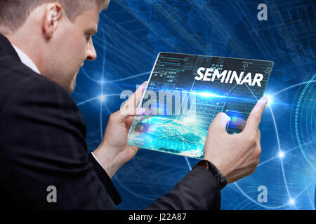Business, technology, internet and networking concept. Young businessman working on his laptop in the office, select the icon seminar on the virtual d Stock Photo