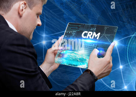 Business, technology, internet and networking concept. Young businessman working on his laptop in the office, select the icon CRM on the virtual displ Stock Photo