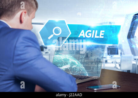 Business, technology, internet and networking concept. Young businessman working on his laptop in the office, select the icon agile on the virtual dis Stock Photo