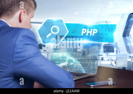 Business, technology, internet and networking concept. Young businessman working on his laptop in the office, select the icon PHP on the virtual displ Stock Photo